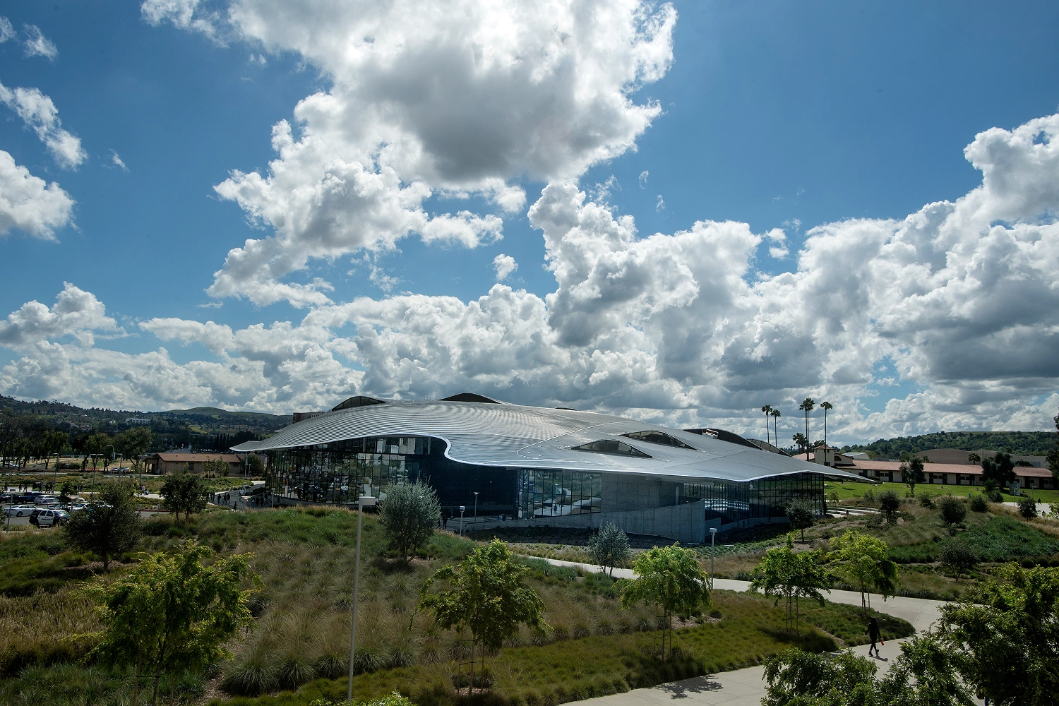 Aerial view of glass-covered university building in campus setting on sunny but cloudy day