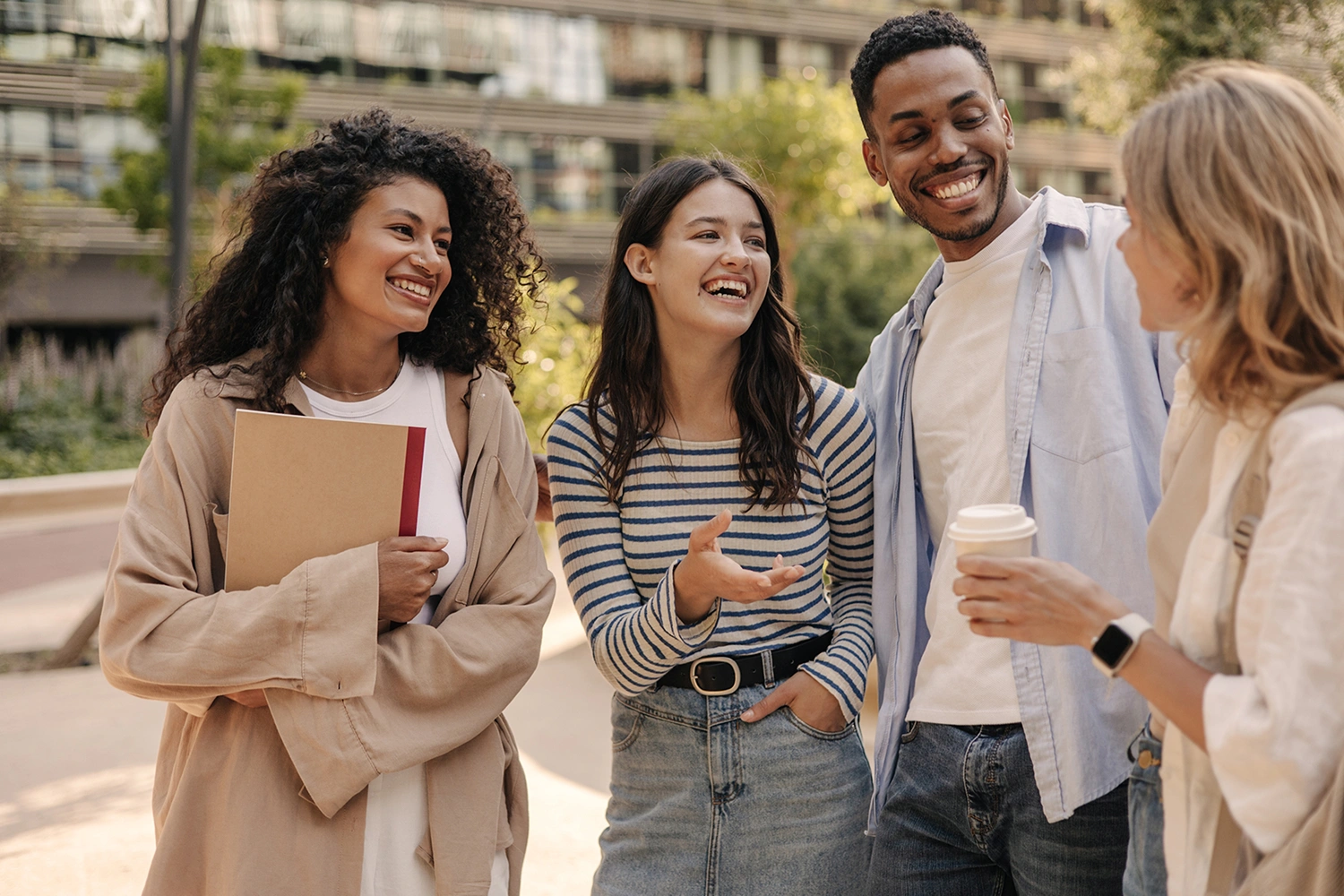 Four university students sharing story during casual meetup on campus-area street