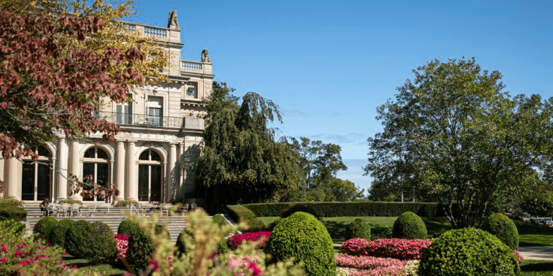 View of campus building and garden on grounds of Monmouth University on clear bright day