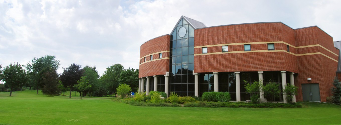 Panoramic view of campus grounds with colonnaded university building on giant lawn near stand of trees