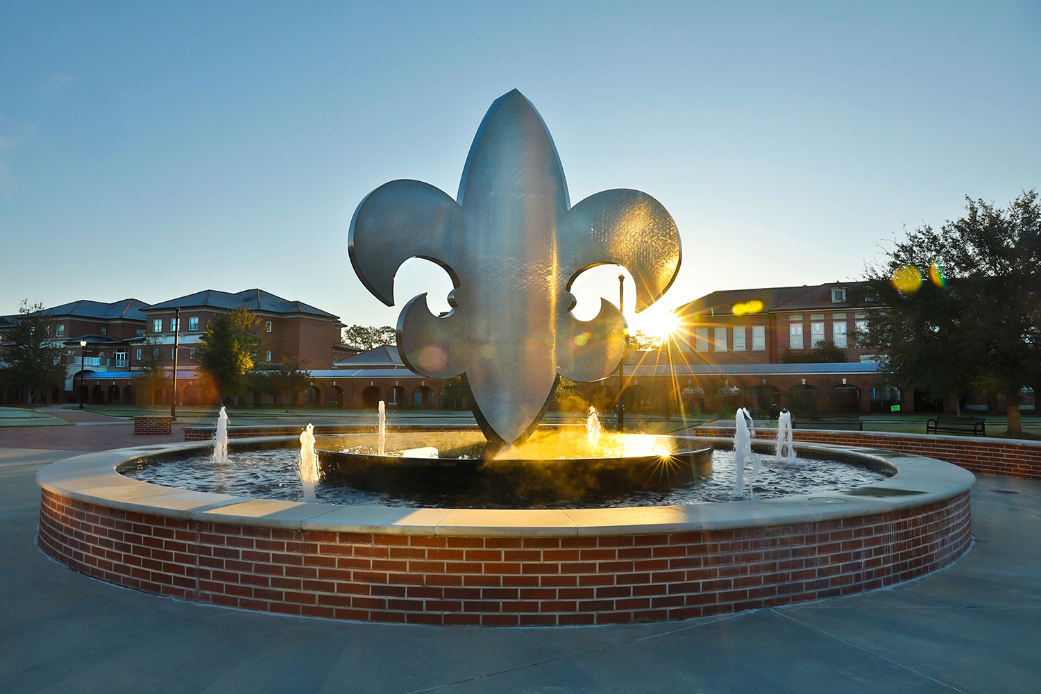 Sunrise over fountain at University of Louisiana at Lafayette featuring large fleur-de-lis installation
