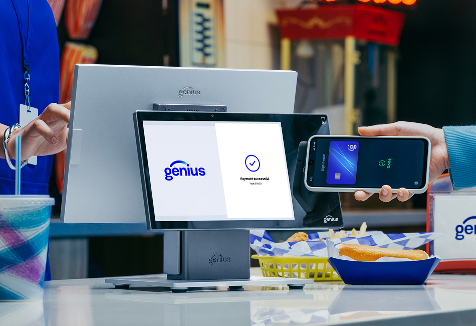 A hand holding a mobile device up to a countertop POS makes a contactless payment.